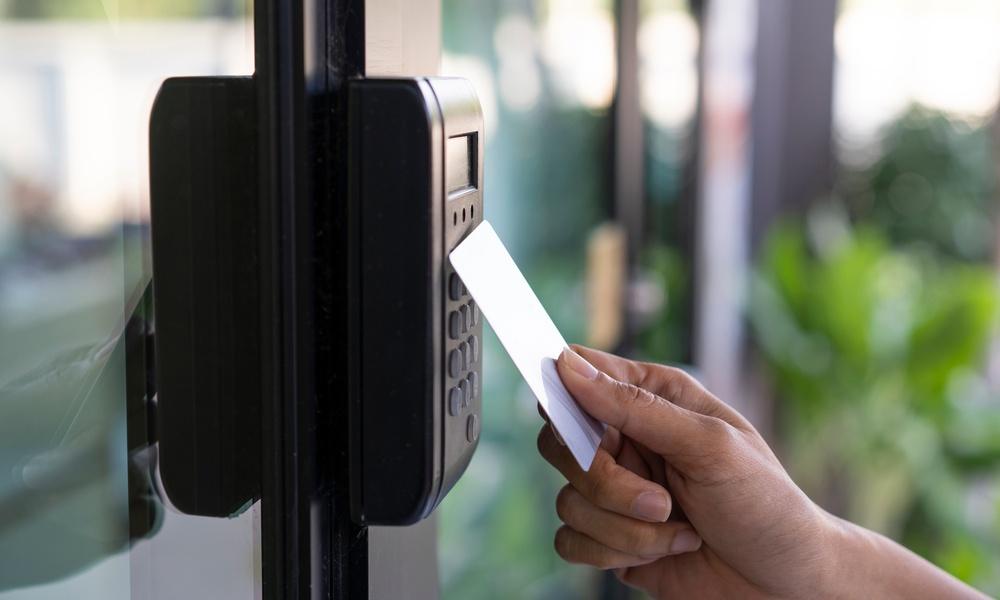 An employee using their white access control keycard to gain entry to a professionally secure building.